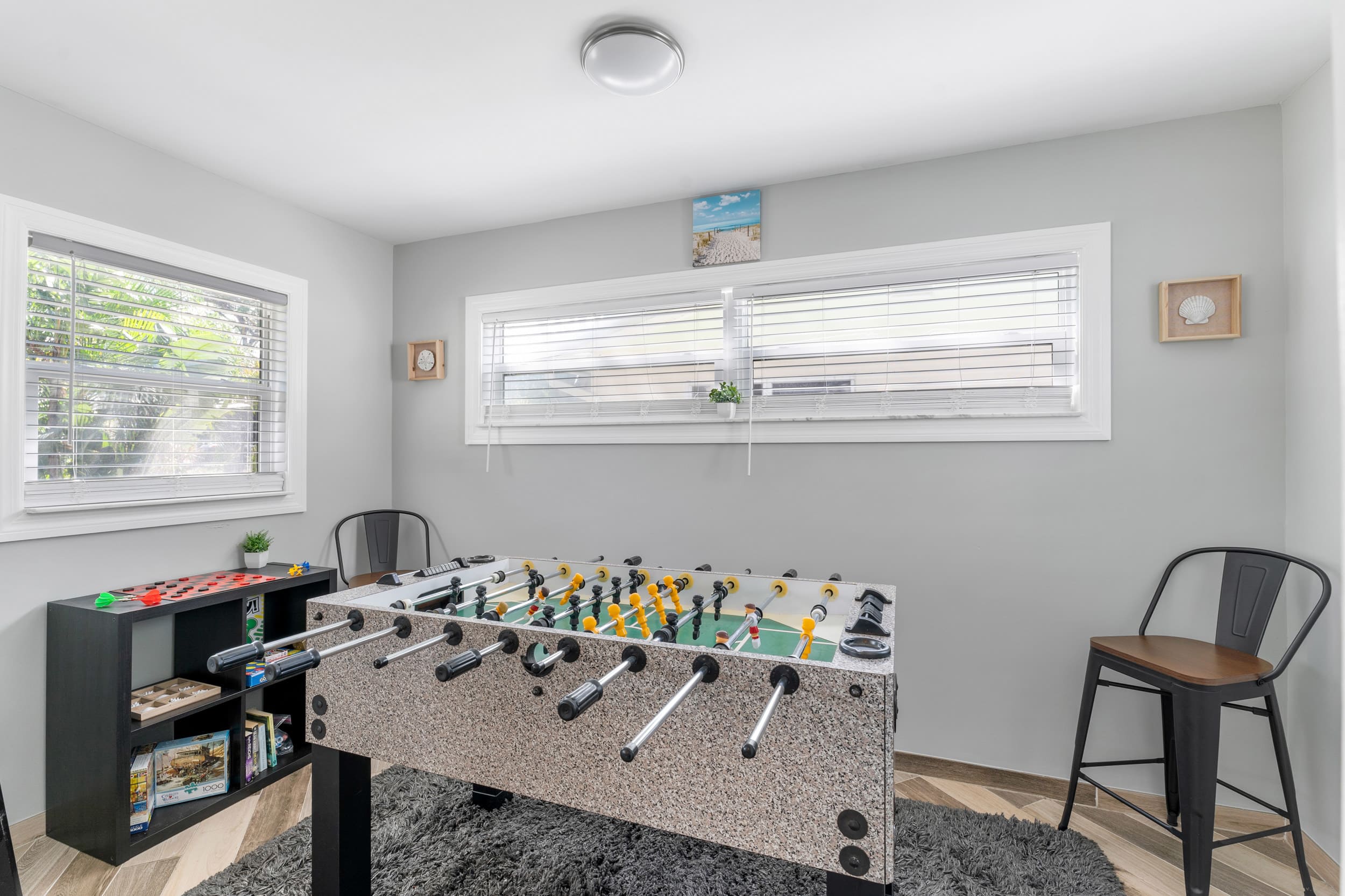 Sun Oasis game room featuring a full-size foosball table, board games, and coastal beach decor — a dedicated space for family fun steps from the living room.