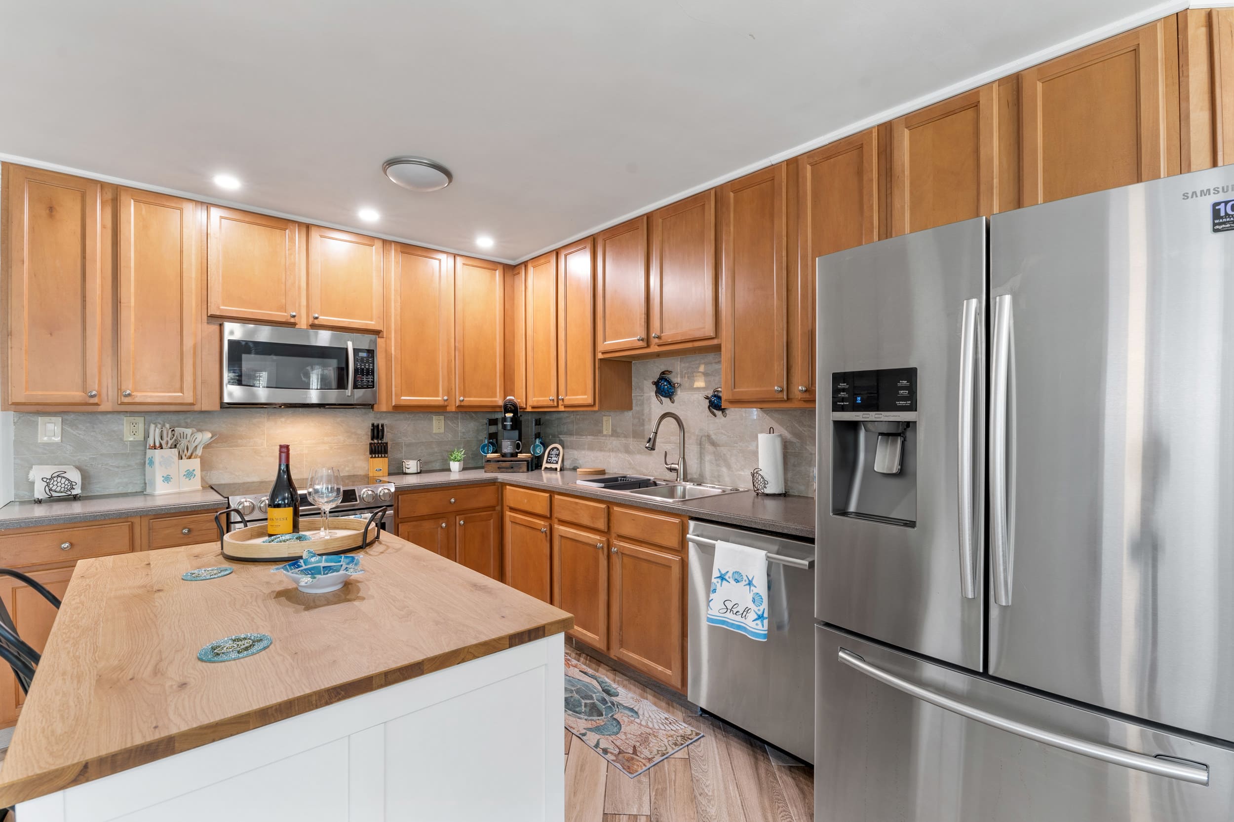 Fully equipped kitchen at Sun Oasis with stainless appliances, warm wood cabinetry, butcher-block island, and playful sea-turtle accents — everything a group needs to cook in style.